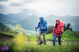 Wanderer mit roter Regenjacke im Wald – Wandern bei Regen Layering