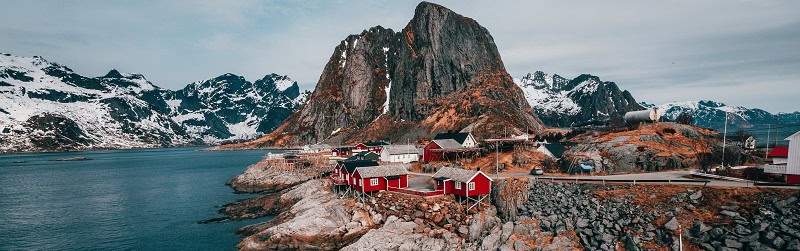 Spektakuläre norwegische Fjord-Landschaft mit traditionellen roten Fischerhütten und schneebedeckten Bergen