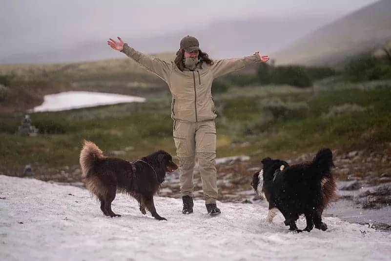 Outdoorbekleidung in Übergrößen – Mann mit zwei Hunden im Schnee in funktionaler Outdoor-Kleidung für große Größen