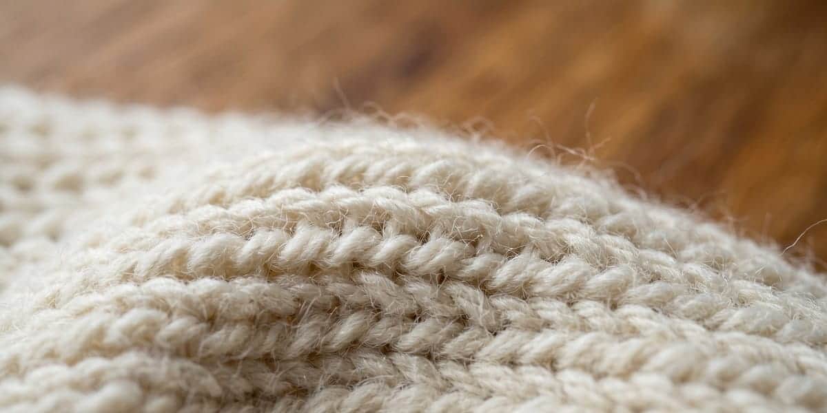 Merinowolle in der Nahaufnahme â die gekrĂ€uselte Faserstruktur sorgt fĂŒr Isolation und ElastizitĂ€t Makroaufnahme der Faserstruktur eines Merinowolle-Strickstoffs in naturweiĂ