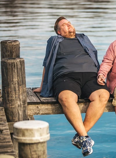 Herr in schwarzer XXL Bermuda entspannt am Steg – kurze Hosen in Übergrößen für Freizeit und Urlaub